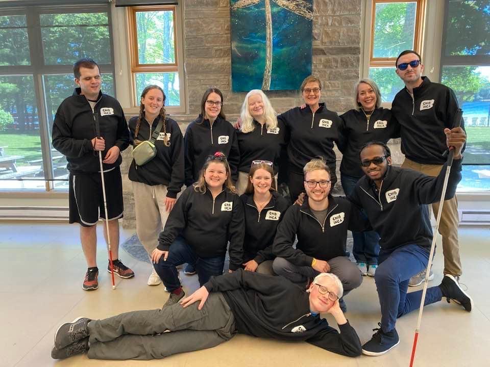 Some members of the CNIB National Youth Council at CNIB Lake Joe. The group poses for a photo in the lounge, standing in front of a window. From Left to right: Taylor, Alicia, Oceanne, Rilind, Caleb, Caelin, Abby, Eitel, Will and Emilee.
