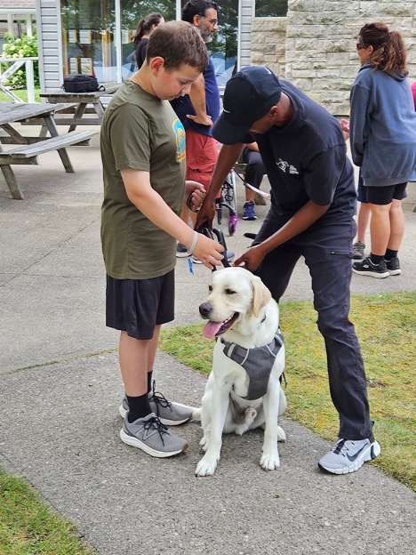 Un jeune participant travaille avec un IMCG à la préparation d’une promenade avec un chien-guide muni d’un harnais.