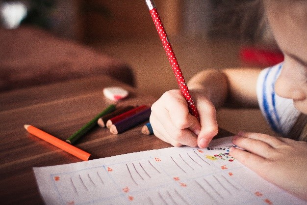 Un enfant écrit avec un crayon au bureau.