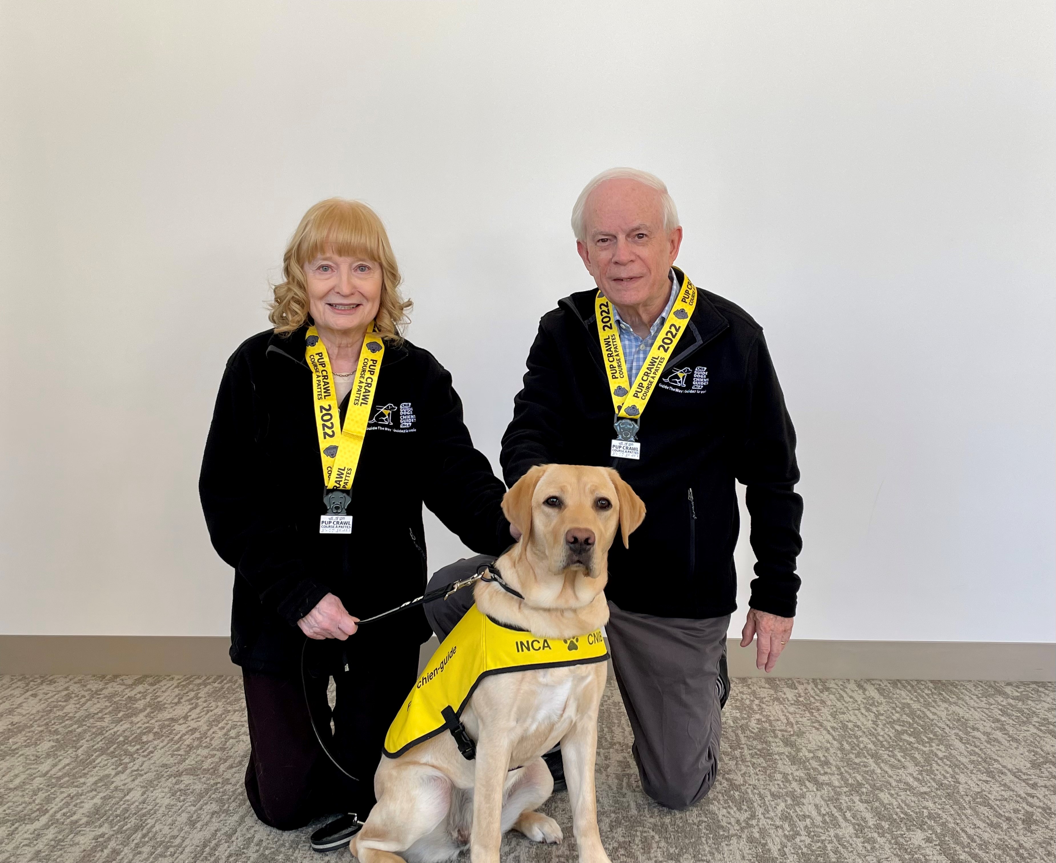 Mary and John Crocker pose with CNIB Guide Dog puppy, Amber, a female yellow Labrador retriever they named following last year's Pup Crawl.