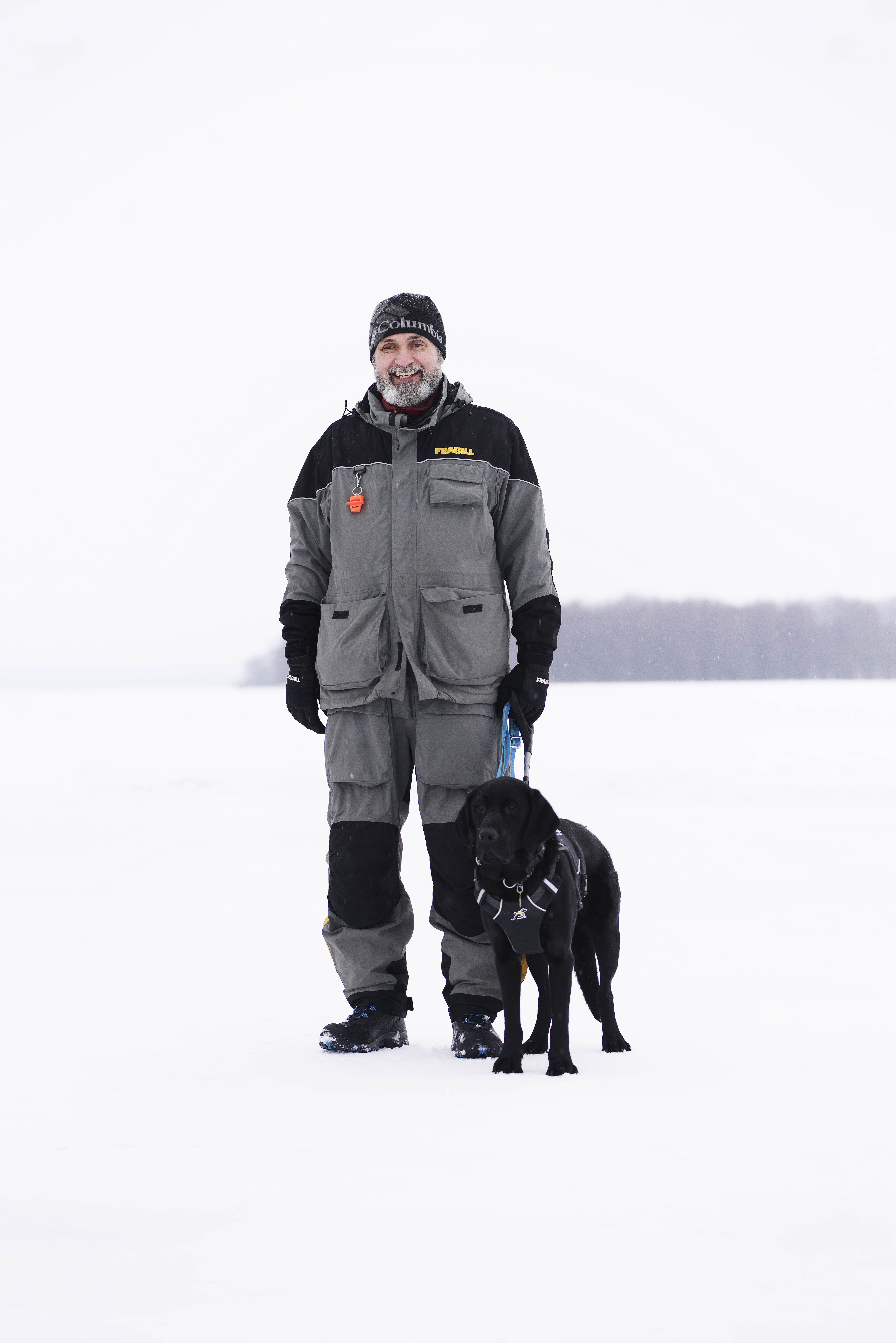 Lawrence and his guide dog enjoying the wintery great outdoors. They stand together on a snow-covered frozen lake.