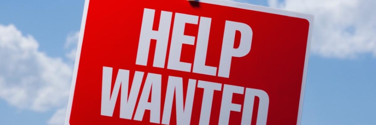  A ‘help wanted’ sign hangs on a clothesline outdoors.