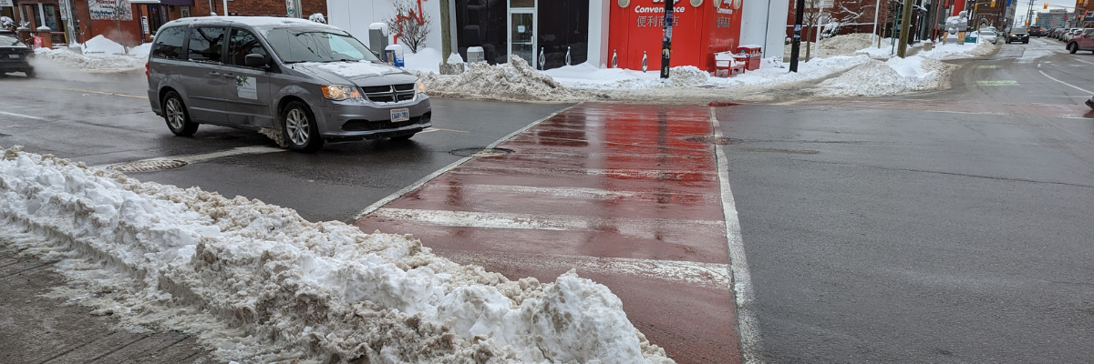  Un amas de neige déblayée bloque le trottoir d’un passage pour piétons très fréquenté. 