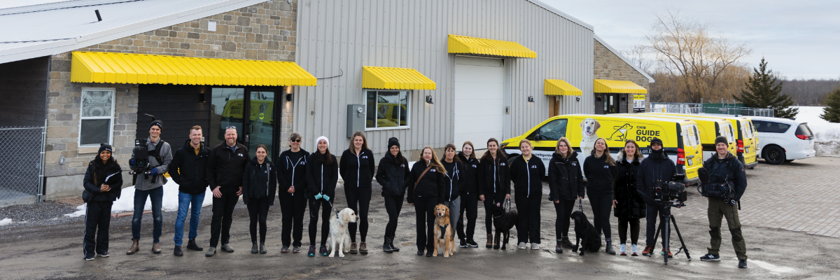 The CNIB Guide Dogs team and the documentary crew pose for a group photo in Carleton Place in front of the CNIB Guide Dogs canine campus.