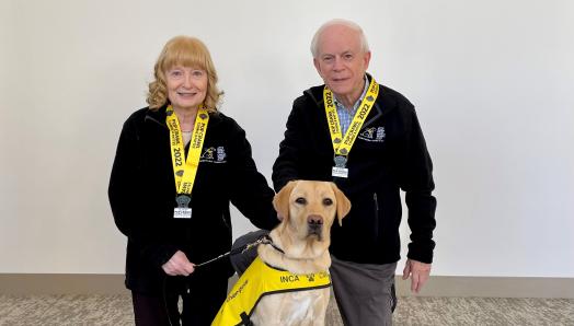 Mary and John Crocker pose with CNIB Guide Dog puppy, Amber, a female yellow Labrador retriever they named after last year’s Pup Crawl.