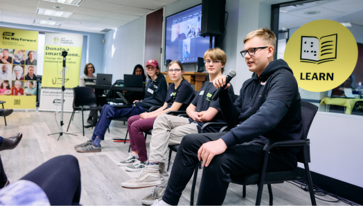 A panel of four youths sit in a line at the front of the room in the CNIB Calgary office