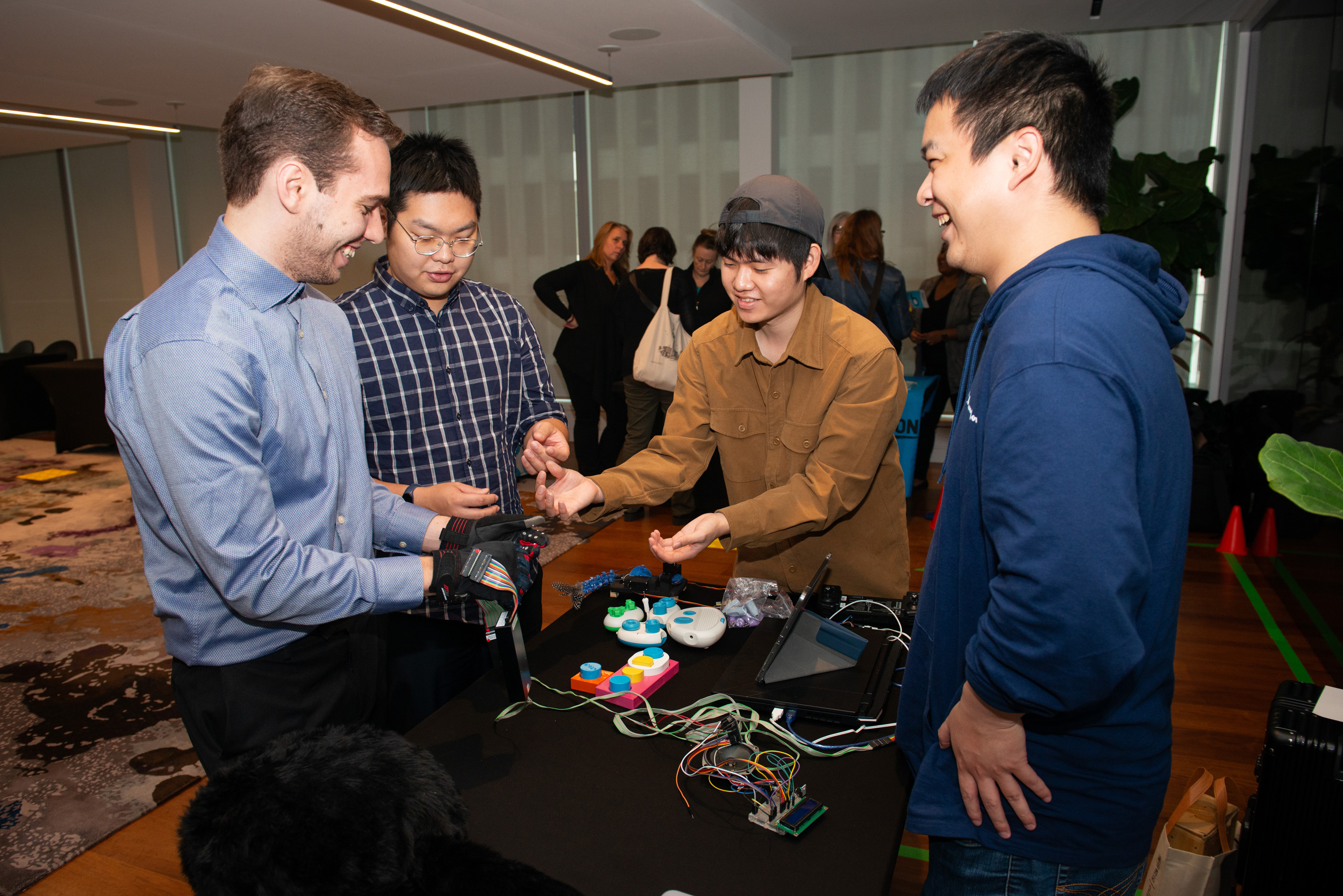 A group of people huddle over a table where some unique tech is being demonstrated. 