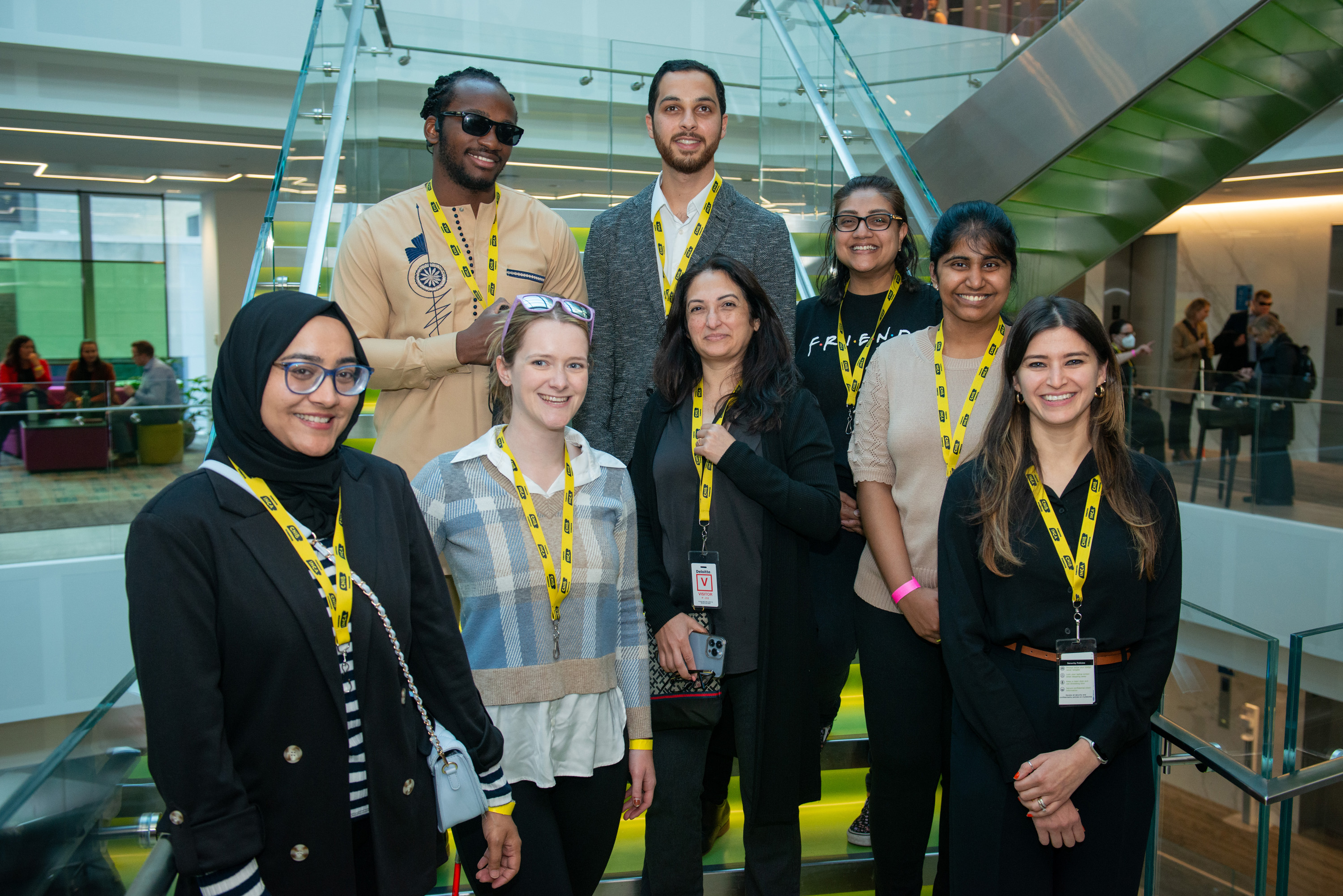 A group of CNIB volunteers wearing yellow CNIB branded lanyards stand together, posing for a photo. 
