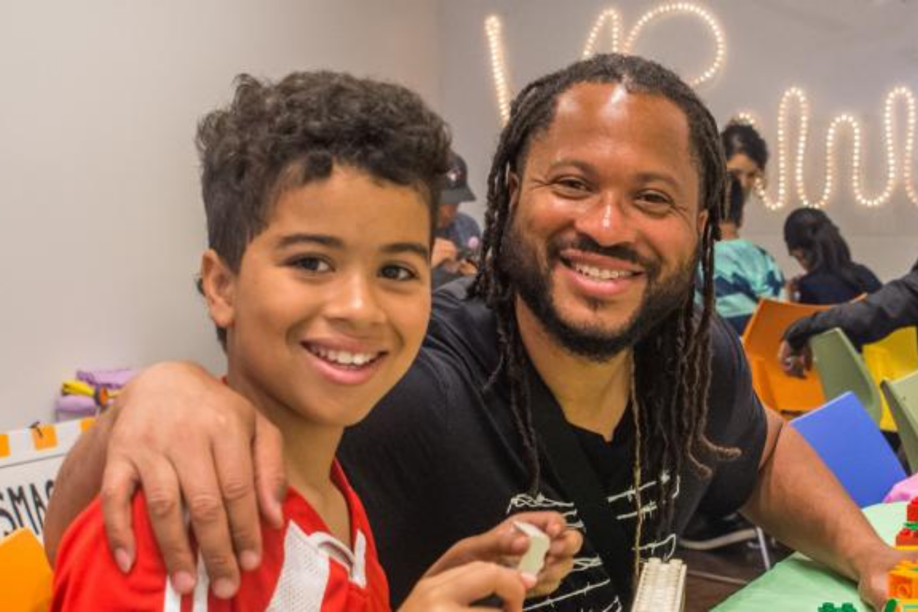 A father and son smiling and building lego. 