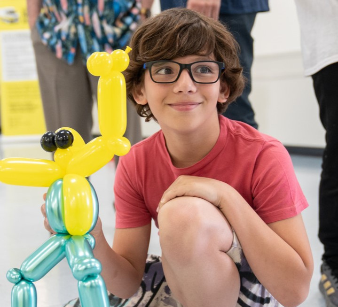 Gabriel, a CNIB Lake Joe camper, poses knelt down with a balloon animal.