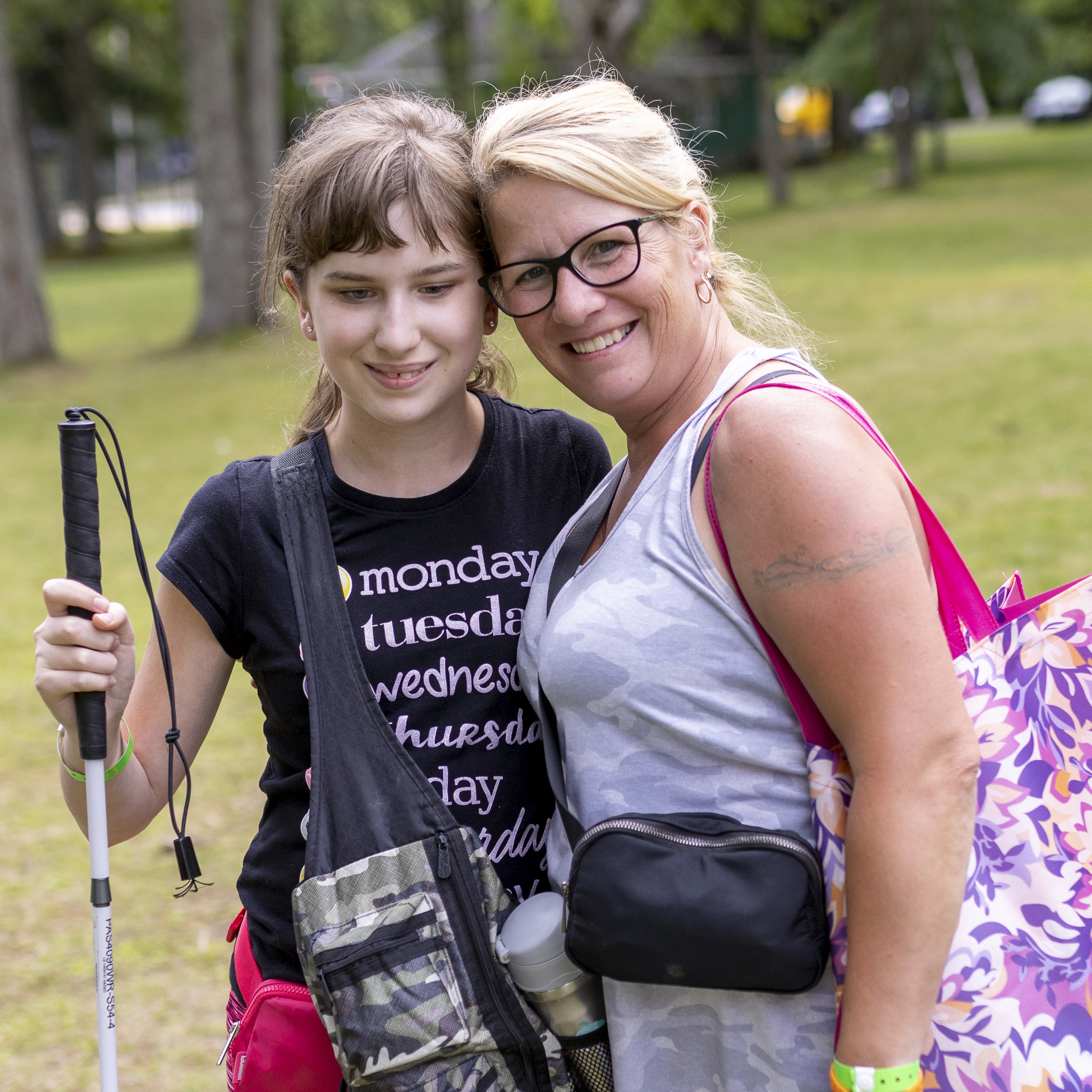 Mother and daughter, both with light skin, smiling - daughter holds a white cane