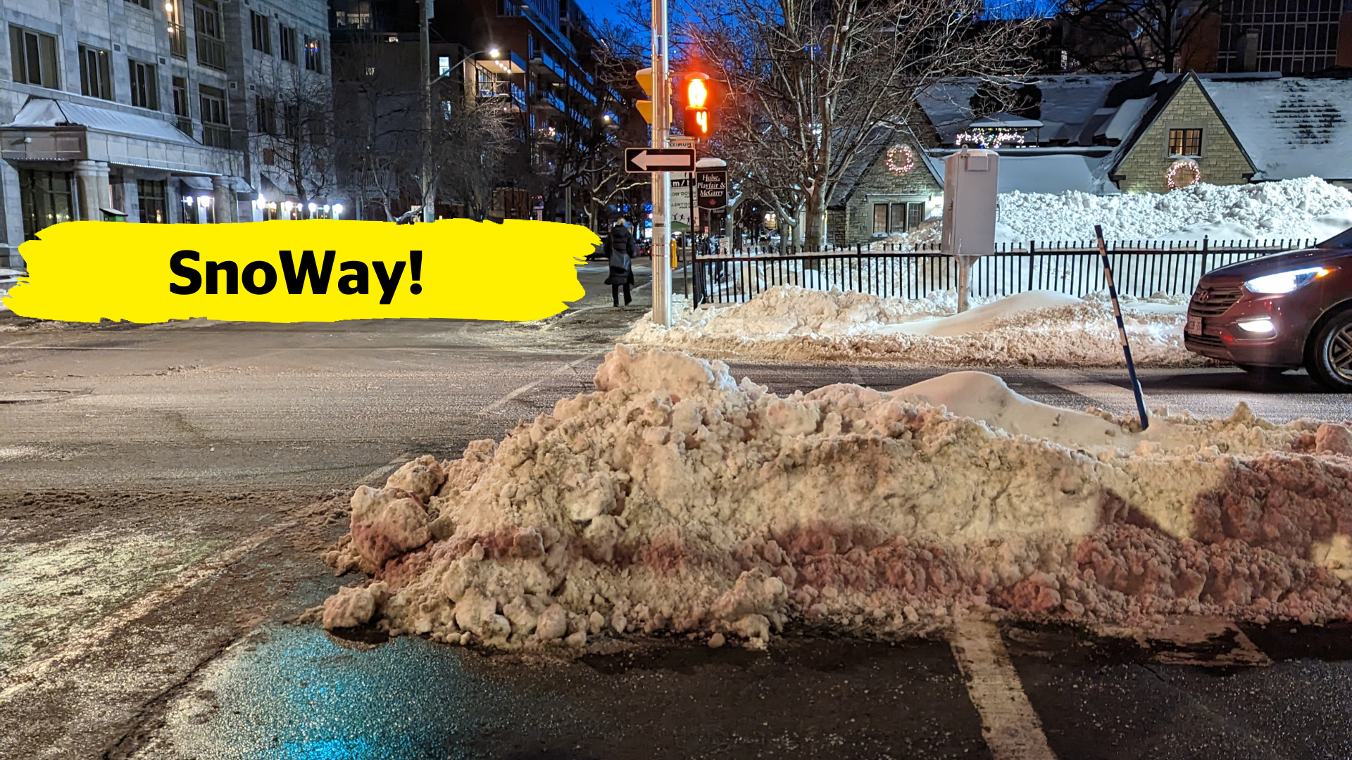 Stopped at traffic lights, a pile of improperly cleared snow blocks half of the pedestrian crosswalk. In the centre of the image, there is a yellow banner overlay with the text “SnoWay!”