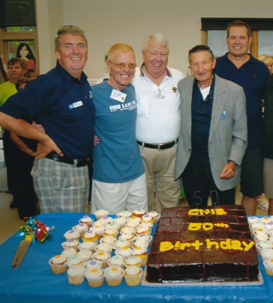 2. A group photo with John Rafferty, Jim Tokos, ?, Walter Gretzy, and Tim Tremain. The group is standing behind a table display of celebratory cupcakes. 