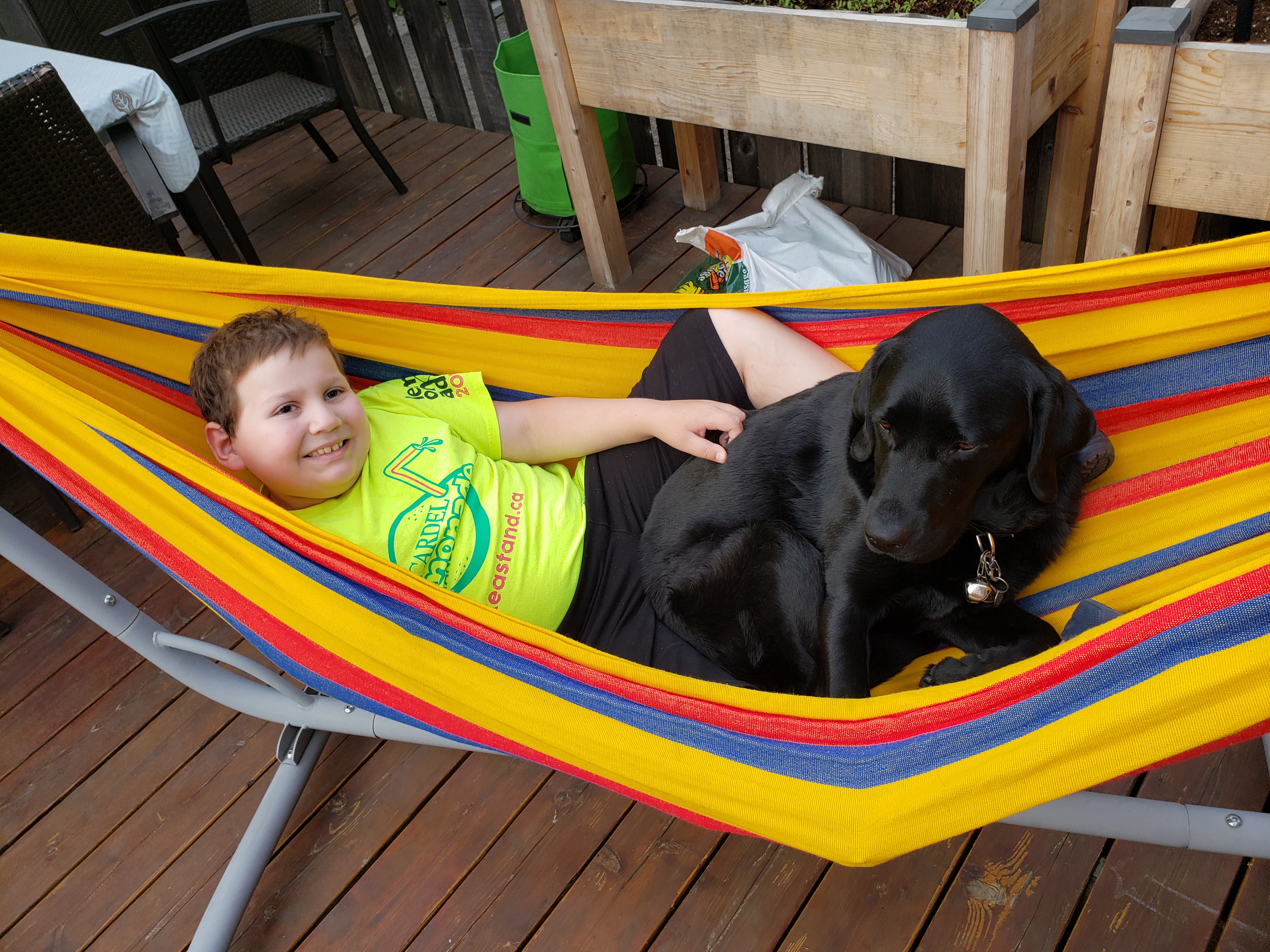 Ollie, a young boy, sits in a hammock at Lake Joe with his buddy dog, Hope, 