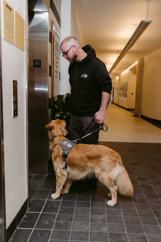 Rob et un chien-guide en formation trouvent une porte d'ascenseur