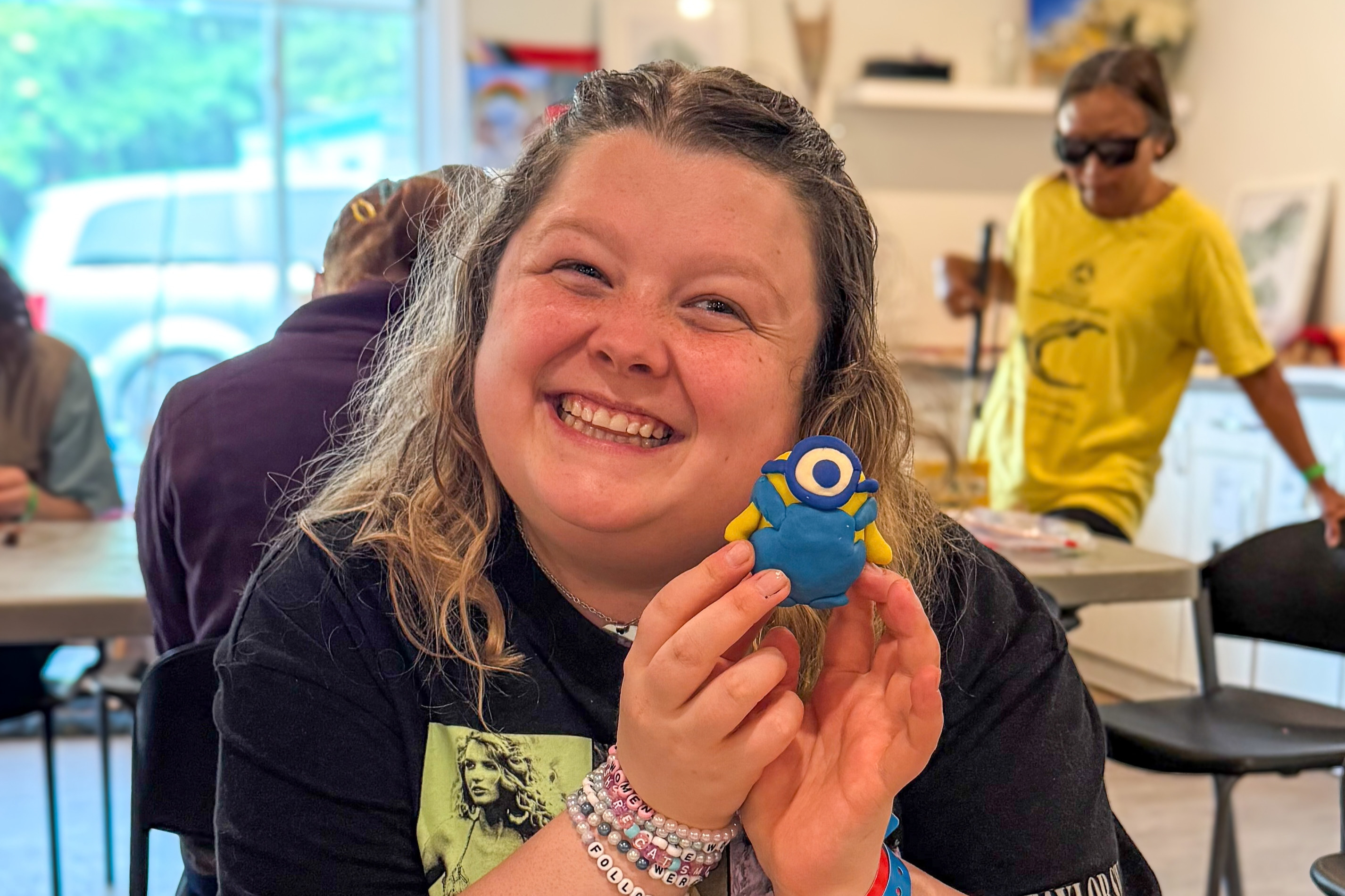 Alicia, a CNIB Lake Joe Young Adults Arts Intensive Week participant, smiles while holding up a small clay sculpture she made.
