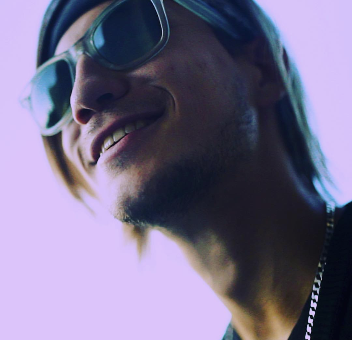 A headshot of Brett Devloo, who is smiling and wearing a bandana and sunglasses.