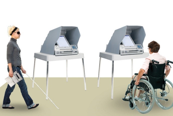 Picture of a woman with a cane walking past an Assistive Voting Device, next to a woman in a wheelchair using a second Assistive Voting Device