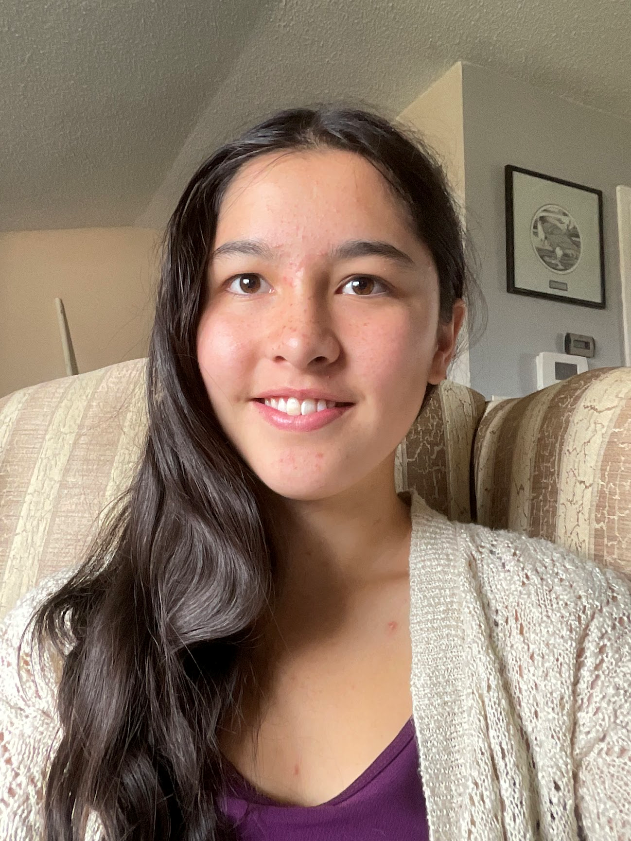 A headshot of Anna Kim smiling while sitting on a couch.