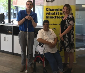 Ryan Hooey poses for a photo at the London Hub with Kristeen Elliott, a Deafblind community member and DBCS Ambassador, and Christine, an Intervenor. 