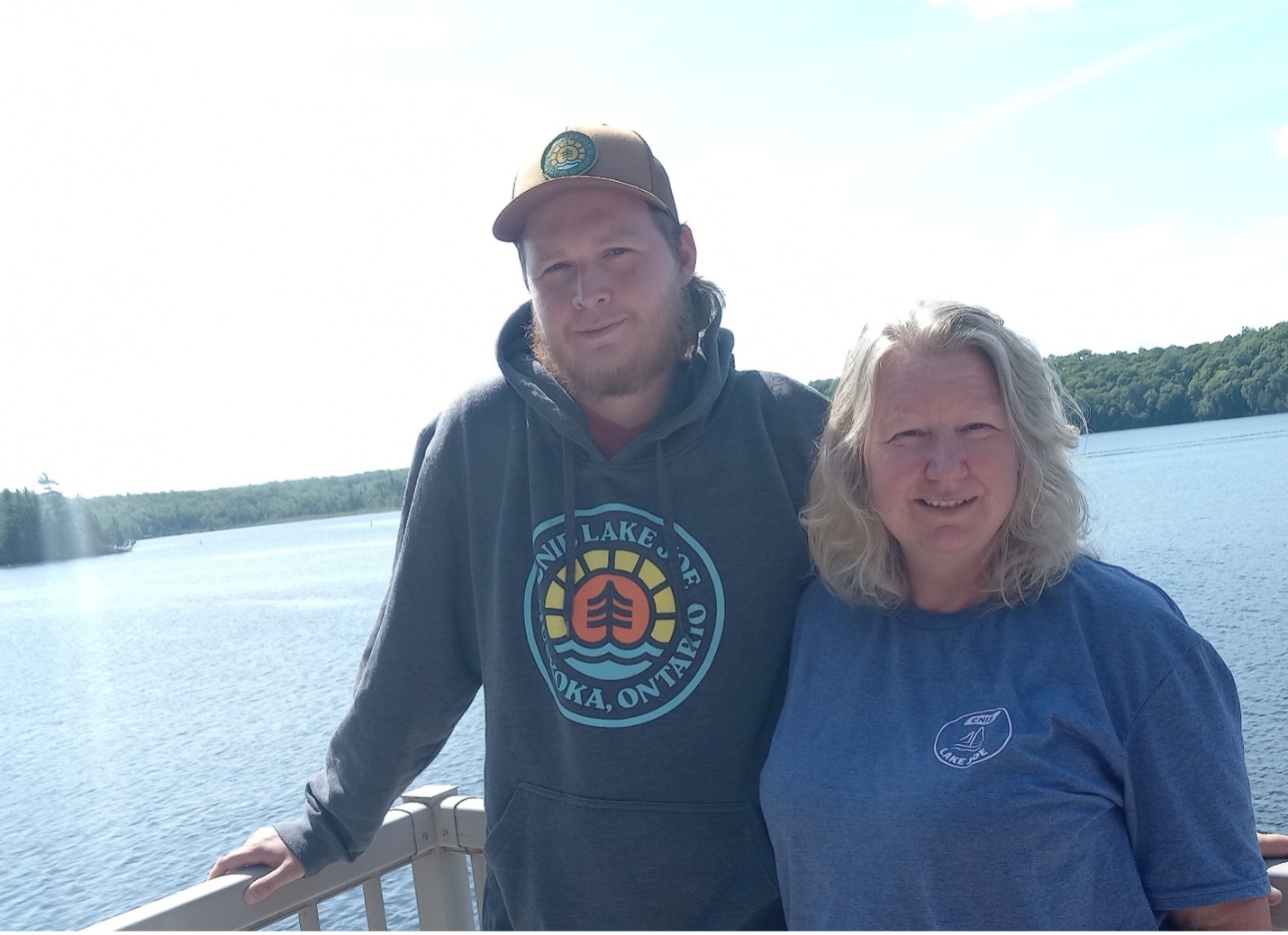 Kathy et son fils Clayton se tiennent sur le balcon de leur chalet, au bord de l’eau.