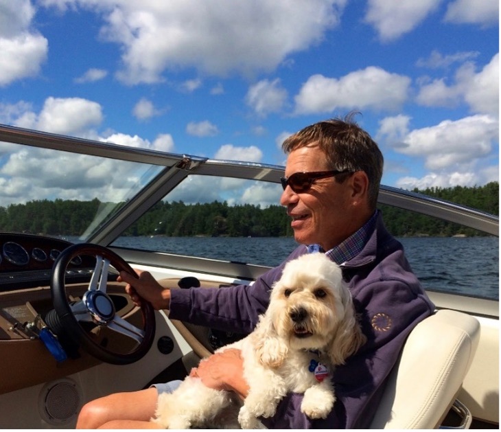 Randall Oliphant conduit un bateau avec un chien sur ses genoux.