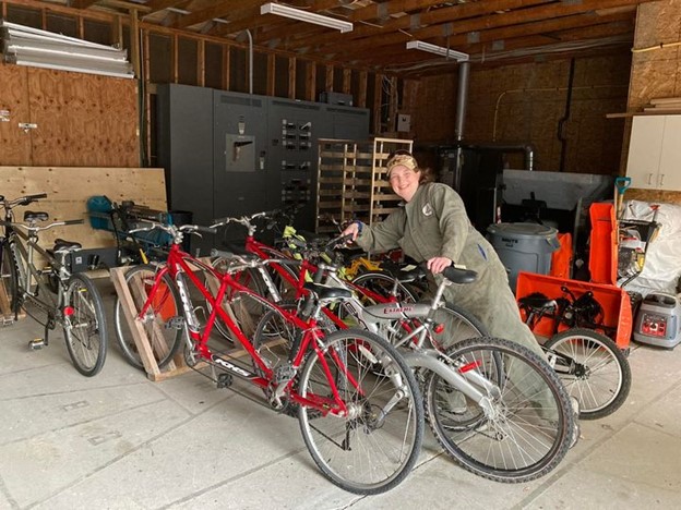 Jessica dans le hangar du Centre Lake Joe d’INCA, vêtue d’une salopette, s’occupe du parc de bicyclettes tandem rouges.