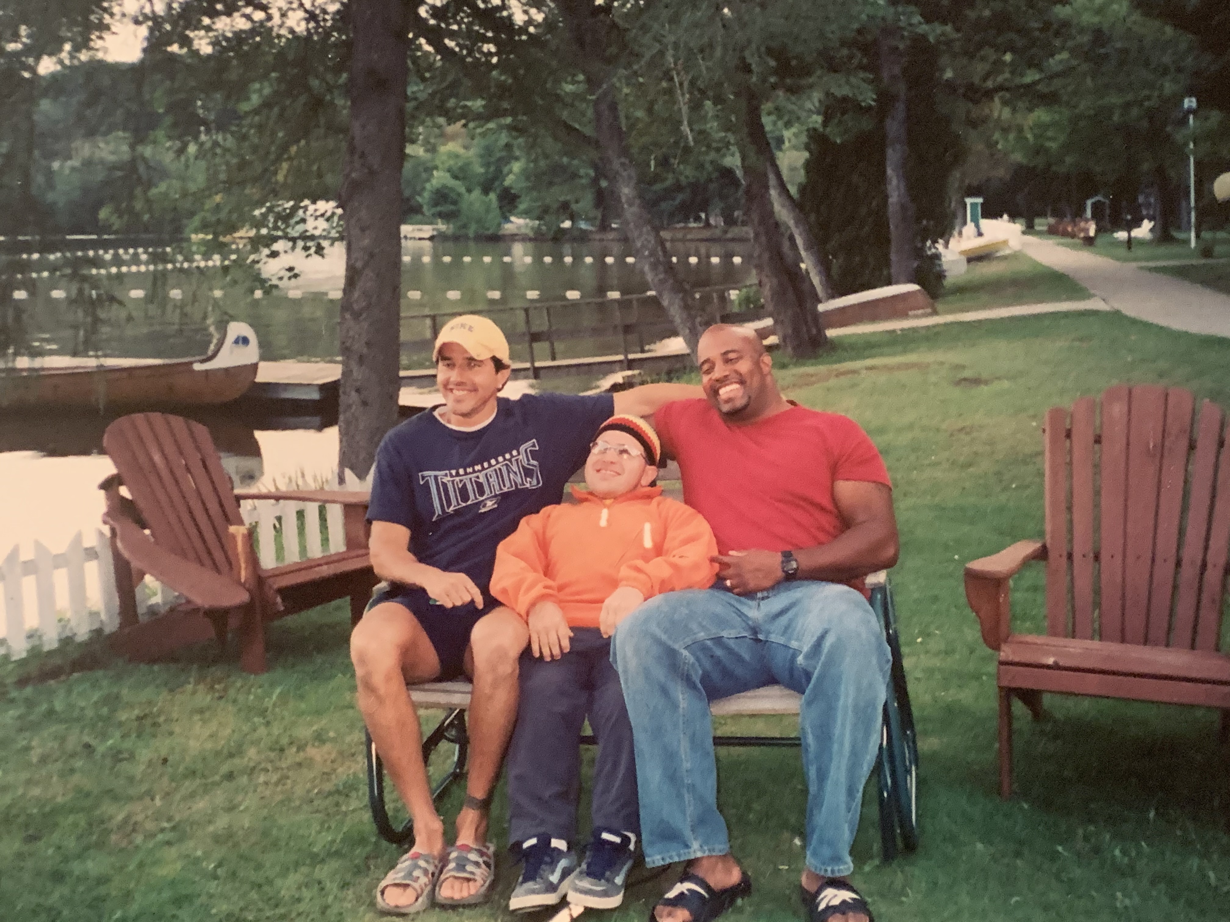 Shawn Dale, Bill Vastis and Derek Thompson sit together on a bench and pose for a group photo on the shoreline of Lake Joe. Their smiles are wide and radiate joy! 