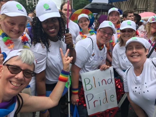 CNIB participants, staff and volunteers sporting white t-shirts and baseball caps in the Pride parade.