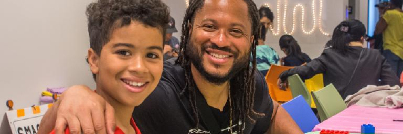 a father and son smiling and building lego. 