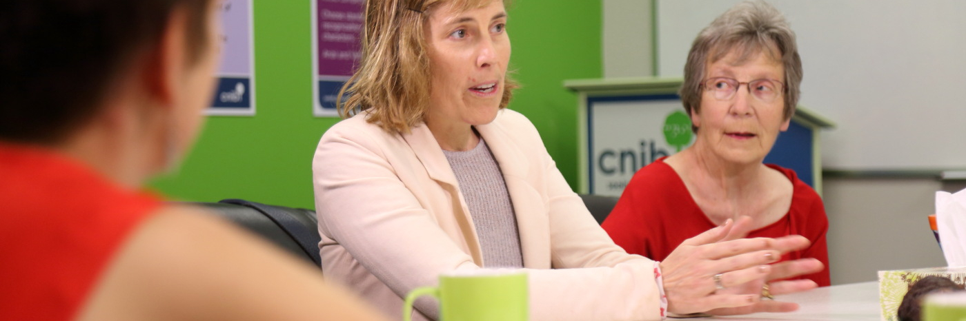 A group of three people sit at a table and engage in lively conversation. 