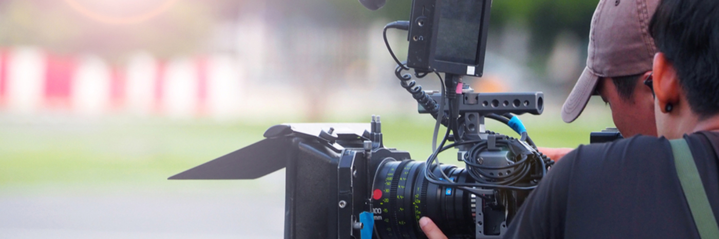 A cinematographer holds a large camera and films. 