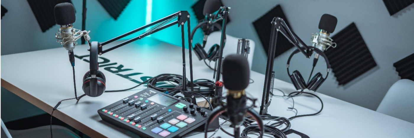 A desk with podcast equipment on top (microphones, headphones, cables, mixer)