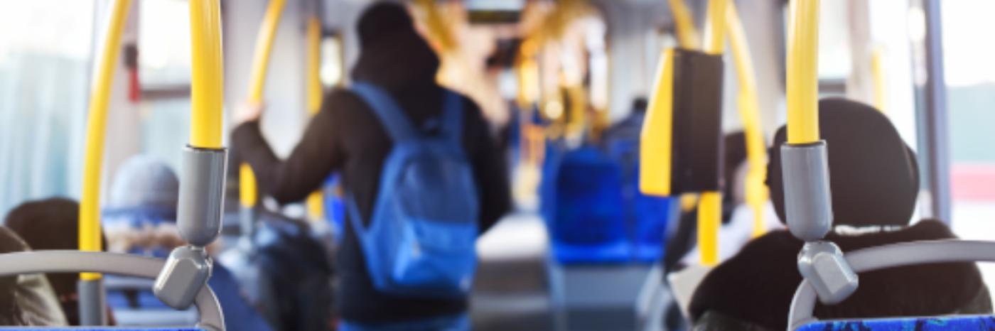 Interior of a city bus. Commuters sit and stand inside the bus.