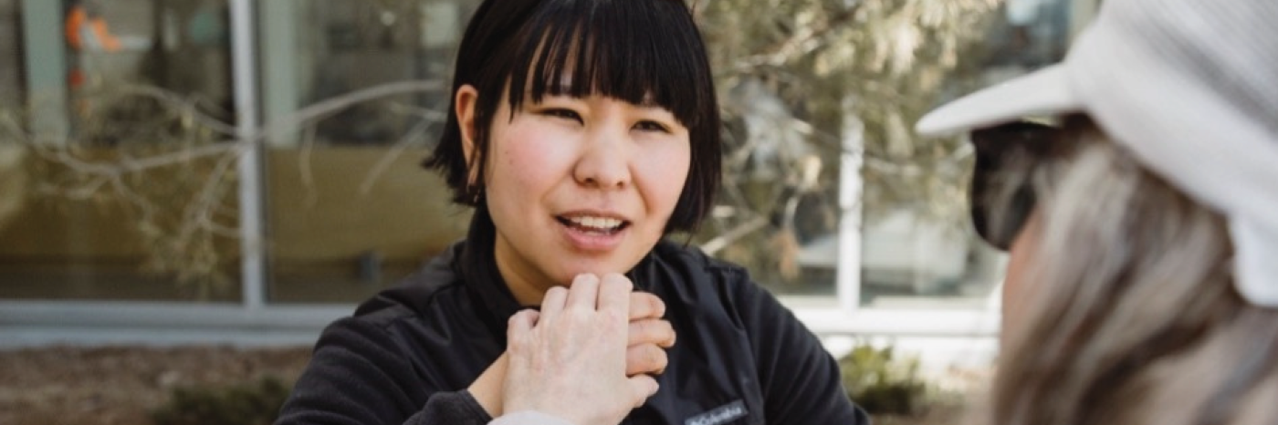 An intervenor uses Tactile American Sign Language (ASL), which involves gently placing the hands over the top of the signers to feel the signs as they are made to communicate with a client.