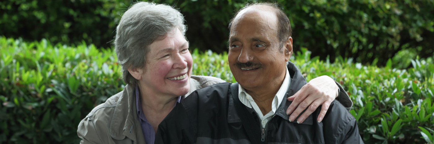 Woman and man sitting on a bench smiling. 