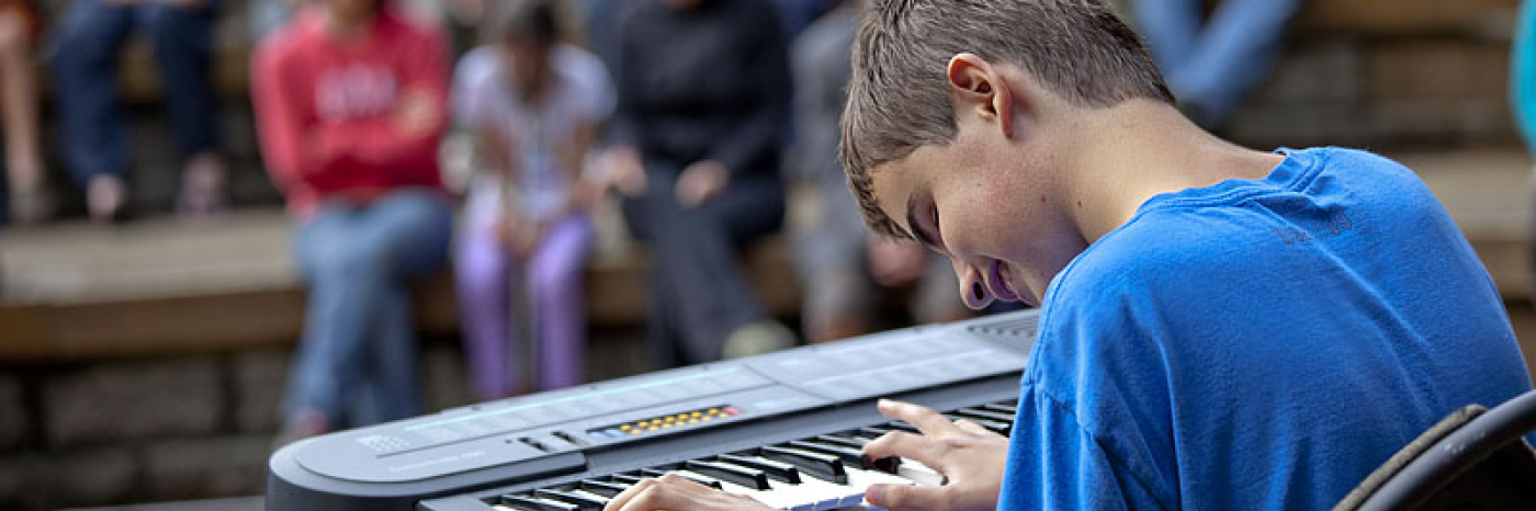 boy with sight loss playing keyboard for a crowd