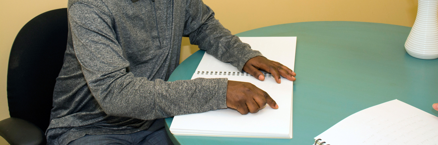 Man with sunglasses reading braille