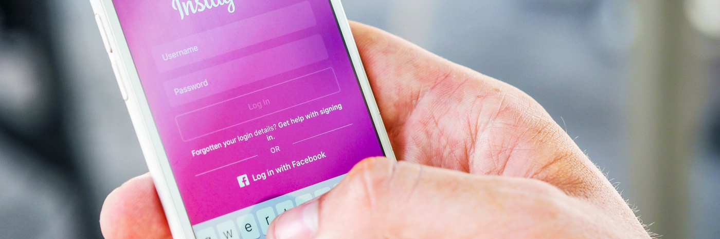 A hand holds up a phone which is open to Instagram.