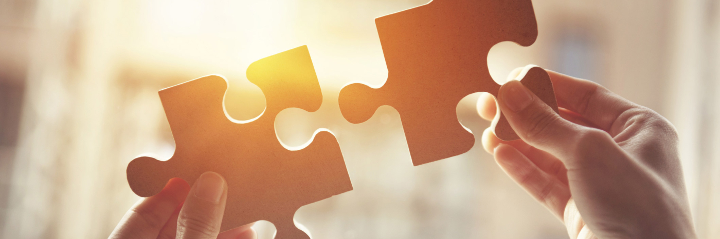 Hands putting two puzzle pieces together