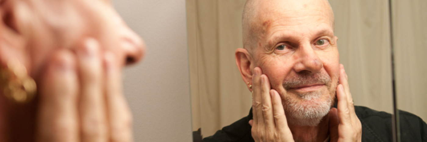 Bald gentleman with goatee looking in mirror.