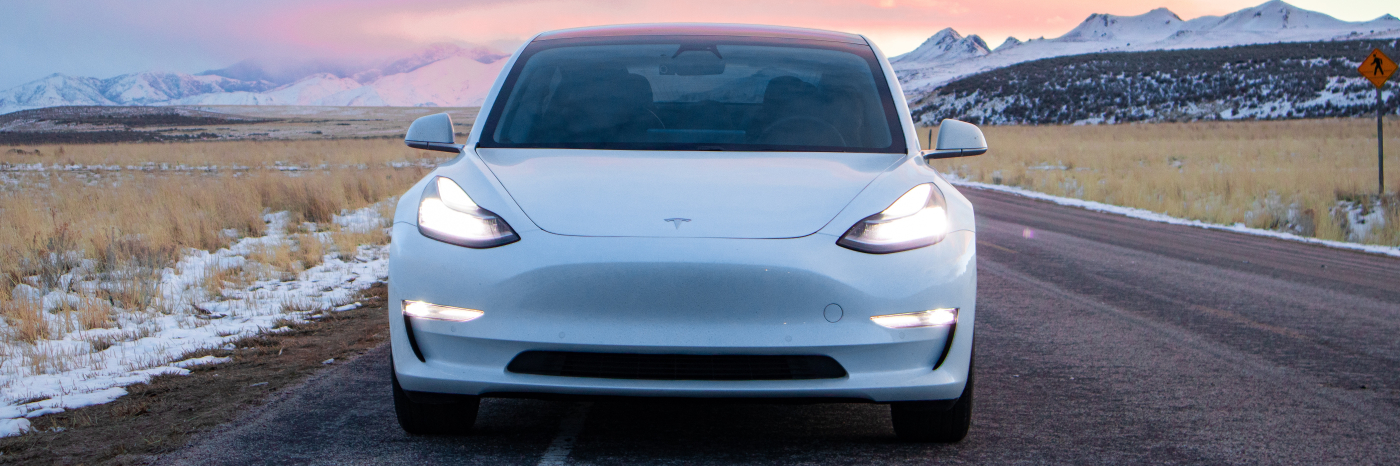A white car drives along an asphalt road.