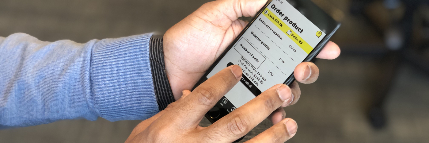 Image of a set of hands holding an iPhone with the Venture Zone Game app open on the screen, displaying the game’s “Add” menu, which lets players choose between various branding, marketing, production or funding options. 