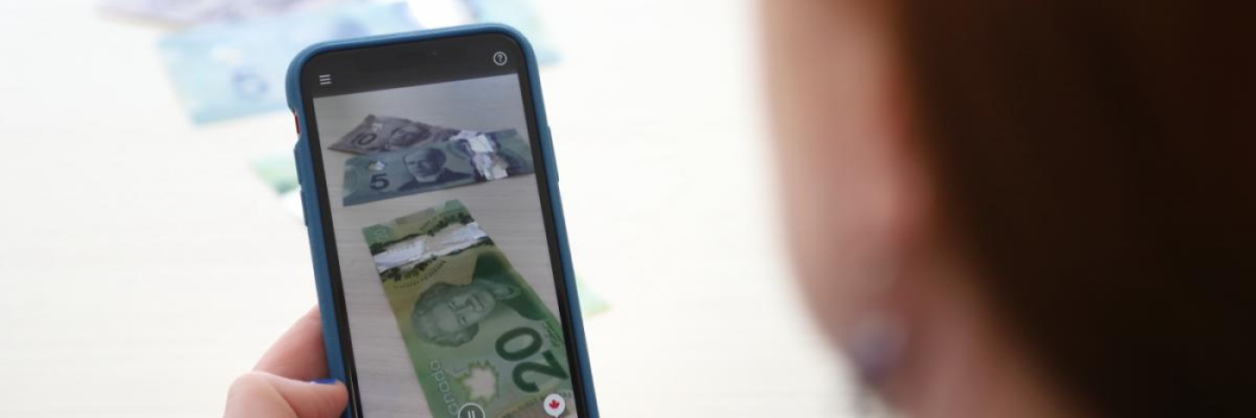 Money appears on the screen of an iPhone with the side of a woman's face in the foreground