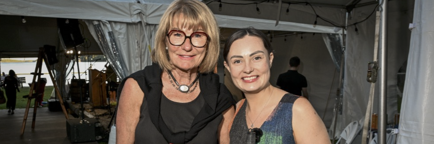 CNIB board member, Jane Savidant (left) and Molly Burke (right) and smile for a posed photo in front of a tent at the Lake Joe Live event.