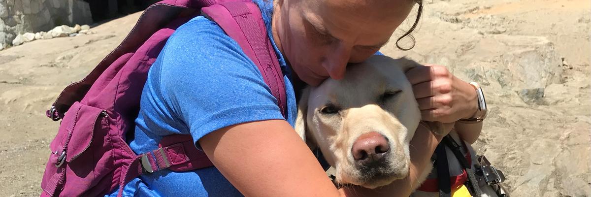 A woman hugs a yellow Labrador Retriever.