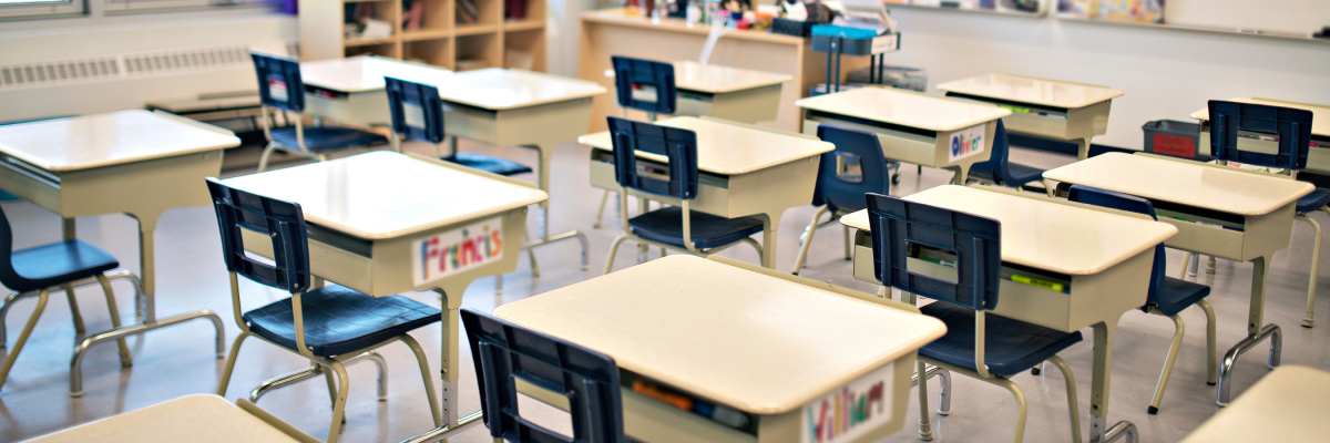 An elementary school classroom with rows of empty desks. 
