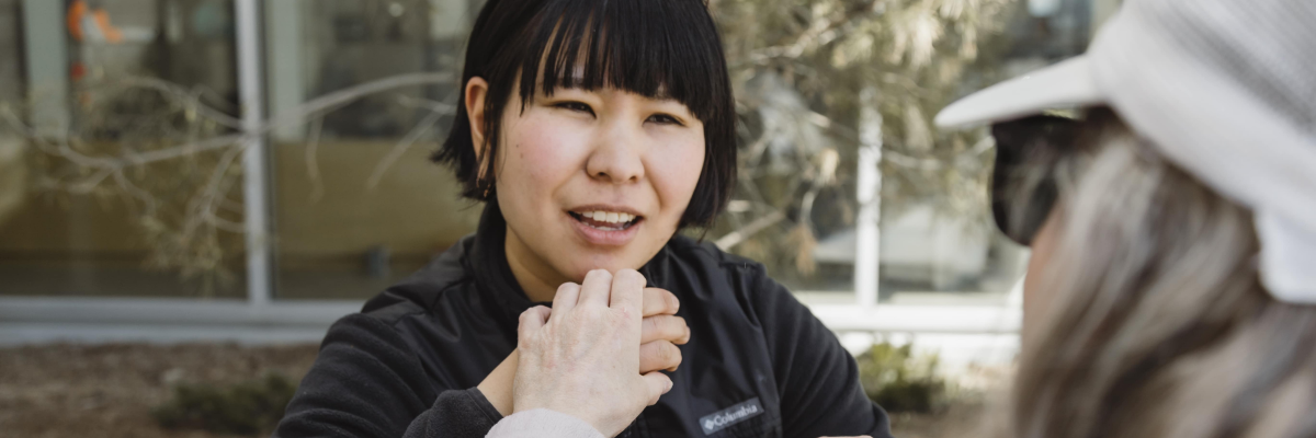 An intervenor uses Tactile American Sign Language (ASL), which involves gently placing their hands over the signer's hands to feel the signs as they are made to communicate with a client.