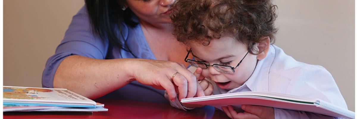 a mother and child read a tactile, braille book.