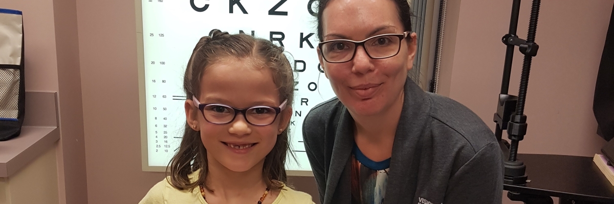 on the right, Teresa Aho, child and family services counsellor, on her left, Violet, holds Nash and her teddy bear, Fluffy. In the back ground is an eye chart.​